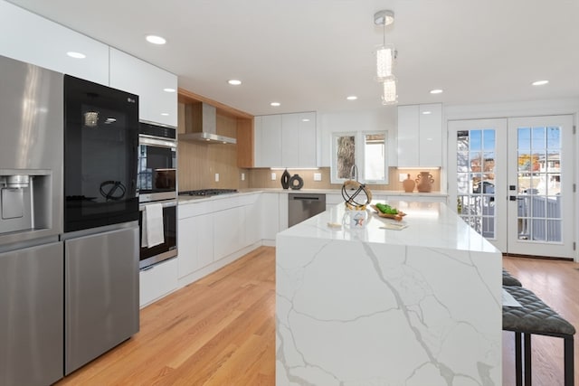 kitchen featuring french doors, white cabinetry, hanging light fixtures, and a healthy amount of sunlight