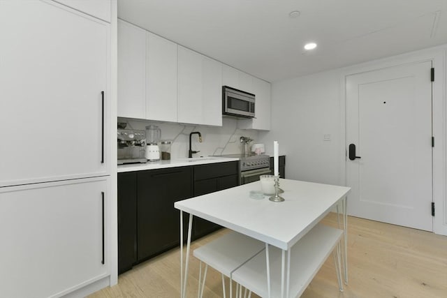 50 Leo M Birmingham Pkwy Unit 405, Boston, MA 02135 - kitchen with appliances with stainless steel finishes, a sink, light countertops, white cabinetry, and light wood-style floors