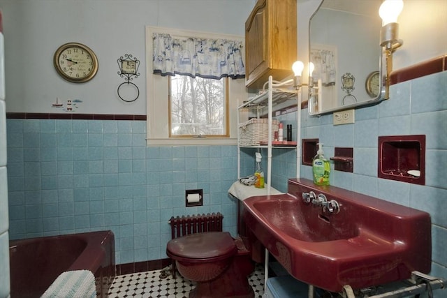 bathroom featuring tile walls, radiator, toilet, a tub, and tile patterned flooring