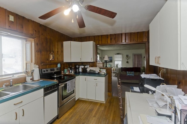 kitchen featuring dishwasher, wooden walls, white cabinetry, and stainless steel electric stove