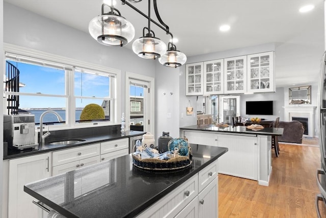 1 W Cliff St, Nahant, MA 01908 - kitchen with a sink, dark countertops, a center island, white cabinets, and glass insert cabinets