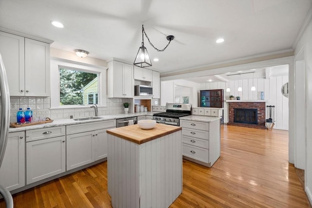 11 Laurel Dr, Scituate, MA 02066 - kitchen featuring wooden counters, appliances with stainless steel finishes, a peninsula, a brick fireplace, and backsplash