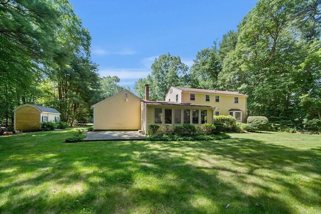 11 Laurel Dr, Scituate, MA 02066 - back of property featuring a chimney, a shed, a patio area, a lawn, and a sunroom