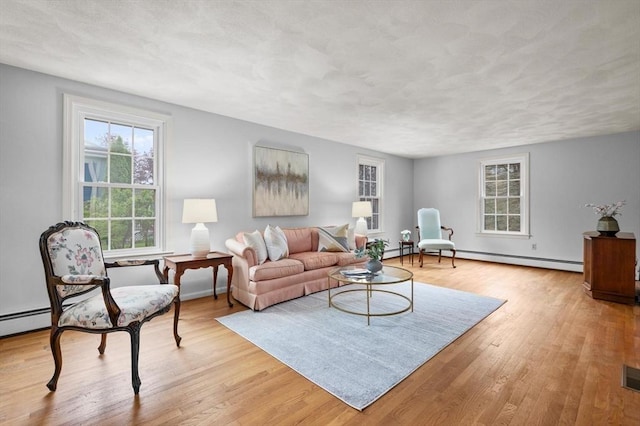 living area featuring a baseboard radiator, light wood-style flooring, and baseboards