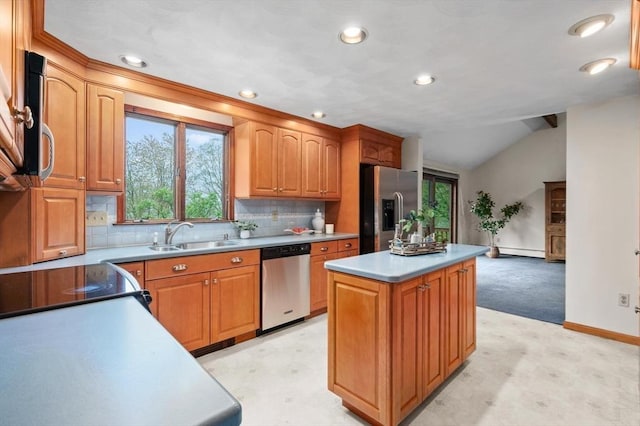 kitchen with appliances with stainless steel finishes, a sink, a center island, baseboards, and backsplash