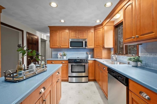 kitchen with stainless steel appliances, a sink, recessed lighting, decorative backsplash, and brown cabinets