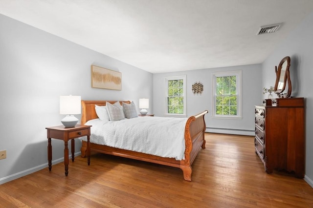 bedroom with wood finished floors, a baseboard radiator, and baseboards