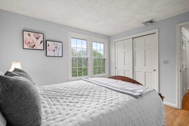 bedroom featuring light wood-type flooring, baseboards, and a closet