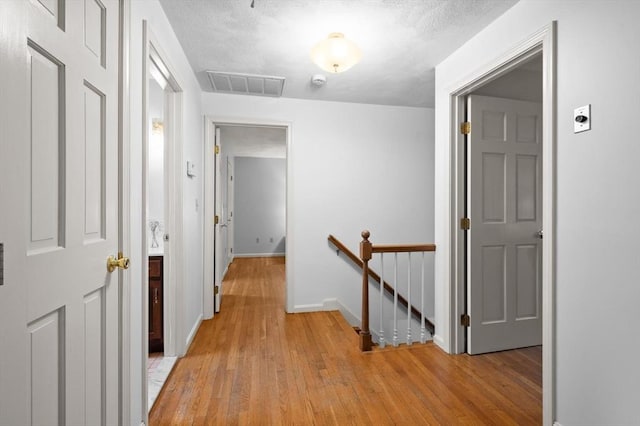 hallway featuring an upstairs landing, light wood-style flooring, and baseboards