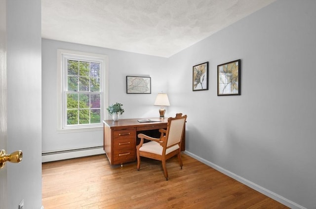 office area with baseboard heating, light wood-style flooring, and baseboards