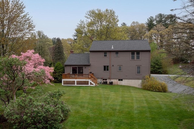 rear view of house featuring a wooden deck, a yard, stairs, and a chimney