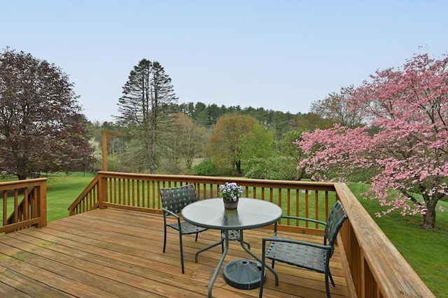 wooden deck featuring a lawn and outdoor dining space