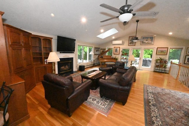 living room featuring a skylight, ceiling fan, light wood finished floors, a fireplace, and recessed lighting