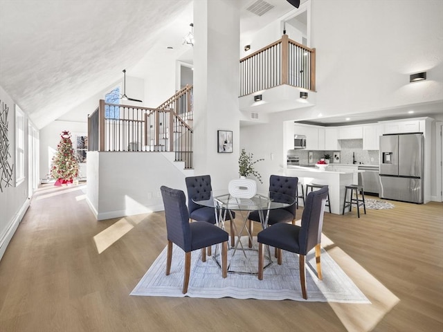 dining room featuring high vaulted ceiling, light hardwood / wood-style flooring, and ceiling fan