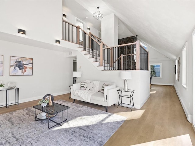 living room featuring lofted ceiling, light wood-type flooring, and an inviting chandelier