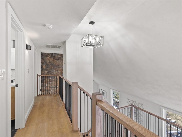 hallway featuring plenty of natural light, light hardwood / wood-style floors, and an inviting chandelier