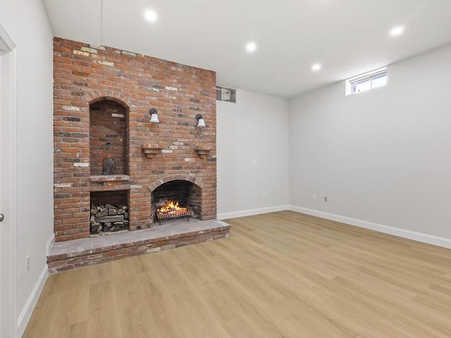 unfurnished living room featuring light hardwood / wood-style floors and a brick fireplace