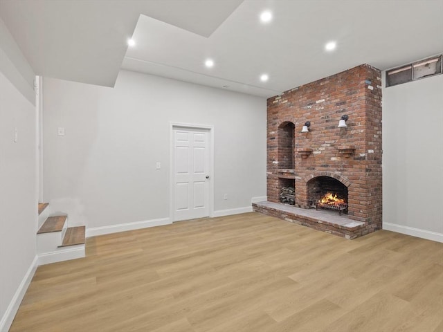 unfurnished living room featuring a brick fireplace and light hardwood / wood-style flooring