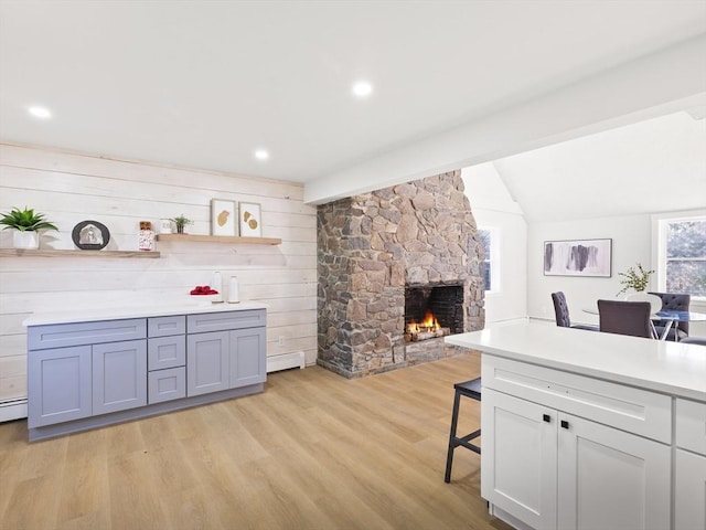 bar with wood walls, a baseboard heating unit, vaulted ceiling, light hardwood / wood-style flooring, and a fireplace