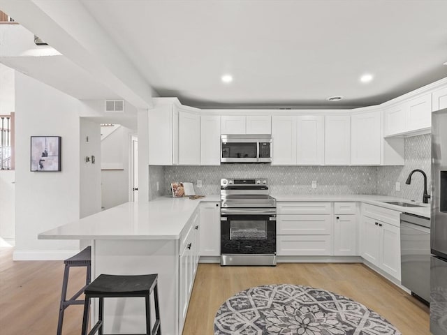 kitchen with light hardwood / wood-style flooring, sink, appliances with stainless steel finishes, and tasteful backsplash