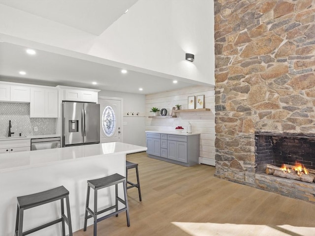 kitchen with sink, stainless steel appliances, light hardwood / wood-style floors, a breakfast bar area, and white cabinets