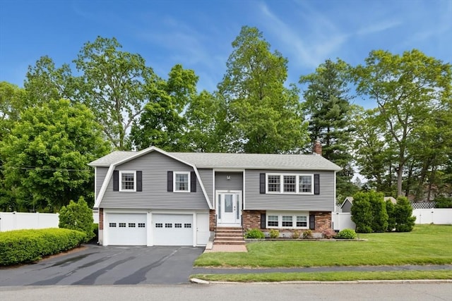 48 W Park Dr, Wakefield, MA 01880 - raised ranch featuring an attached garage, asphalt driveway, a chimney, entry steps, and view of wooded area
