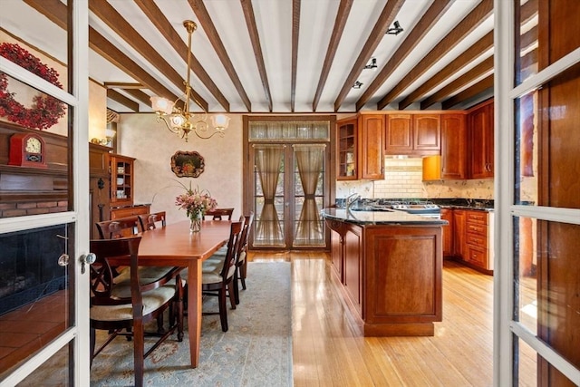 kitchen featuring light wood-type flooring, beam ceiling, dark countertops, and brown cabinetry