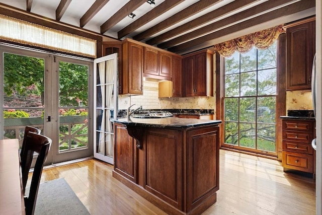 kitchen with beamed ceiling, light wood-type flooring, and a sink