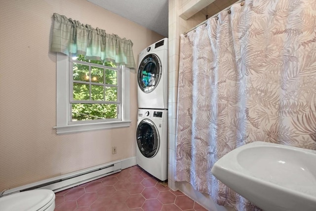 laundry room featuring laundry area, dark tile patterned flooring, a sink, stacked washer / dryer, and baseboard heating