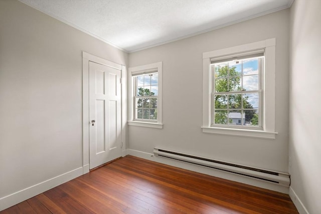 empty room with baseboard heating, a healthy amount of sunlight, baseboards, and dark wood-style flooring