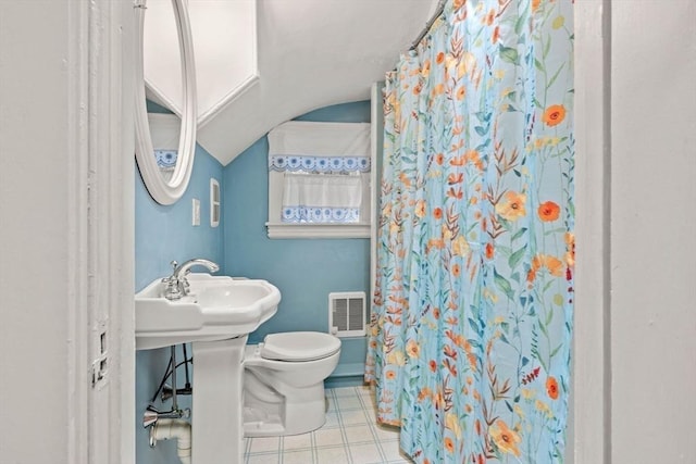 bathroom featuring a shower with shower curtain, visible vents, a sink, vaulted ceiling, and toilet