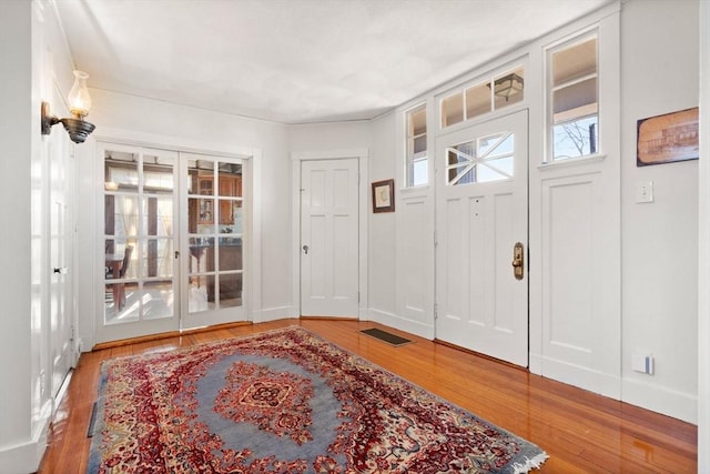 entrance foyer with wood finished floors, visible vents, french doors, and baseboards