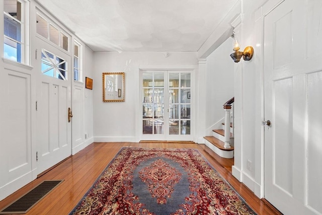 foyer entrance featuring visible vents, stairs, baseboards, and hardwood / wood-style floors