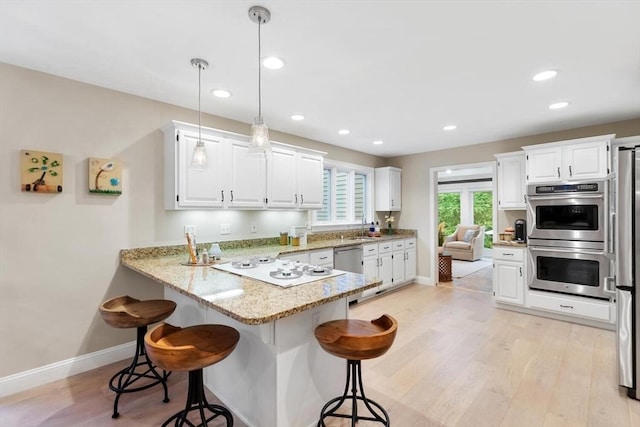 1 Preston Cir, Andover, MA 01810 - kitchen featuring appliances with stainless steel finishes, a peninsula, a kitchen breakfast bar, white cabinetry, and light wood finished floors