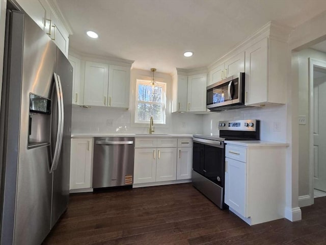 kitchen with sink, dark wood-type flooring, hanging light fixtures, stainless steel appliances, and white cabinets