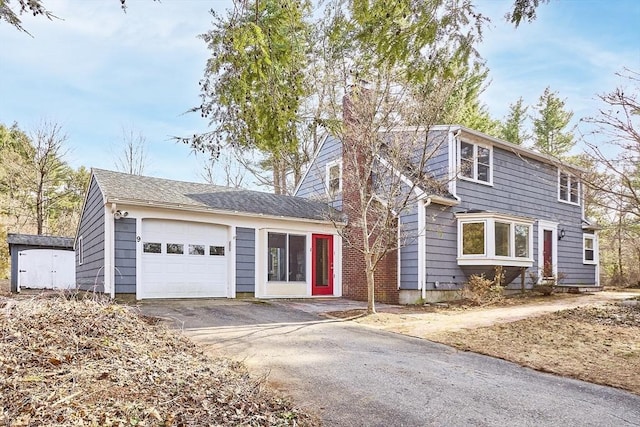 view of front facade with a garage, driveway, and a chimney