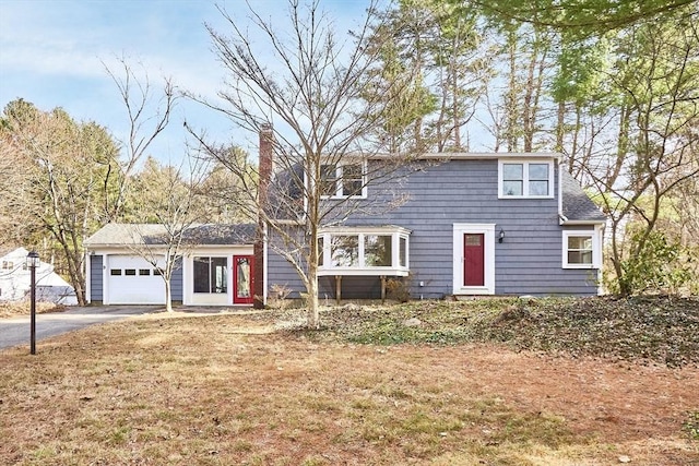 view of front of house with aphalt driveway, a garage, roof with shingles, and a chimney