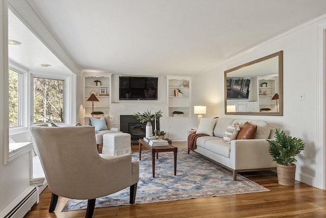 living room with built in shelves, wood finished floors, and a baseboard radiator