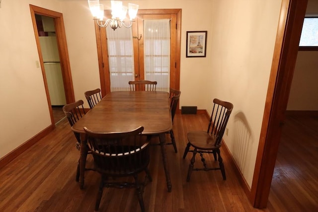 dining space with baseboards, an inviting chandelier, and wood finished floors