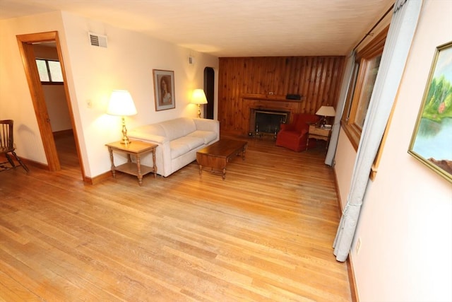 living room with baseboards, visible vents, arched walkways, light wood-type flooring, and a fireplace