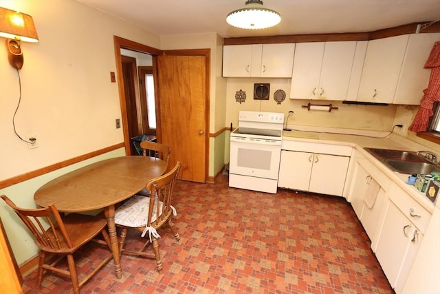 kitchen featuring light countertops, a sink, white range with electric stovetop, and white cabinetry