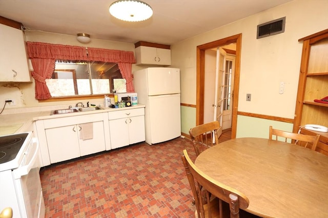 kitchen with light countertops, visible vents, white cabinetry, a sink, and white appliances