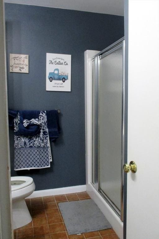 bathroom with toilet, tile patterned flooring, and a shower with door