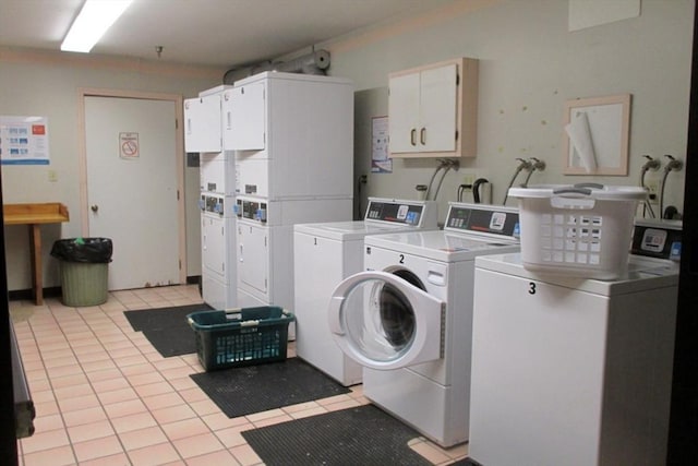 clothes washing area with washer and dryer, cabinets, stacked washer / dryer, and light tile patterned floors