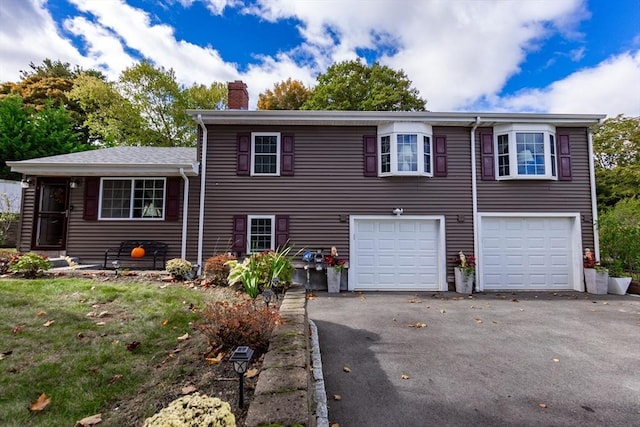 split level home with a chimney, a garage, and aphalt driveway