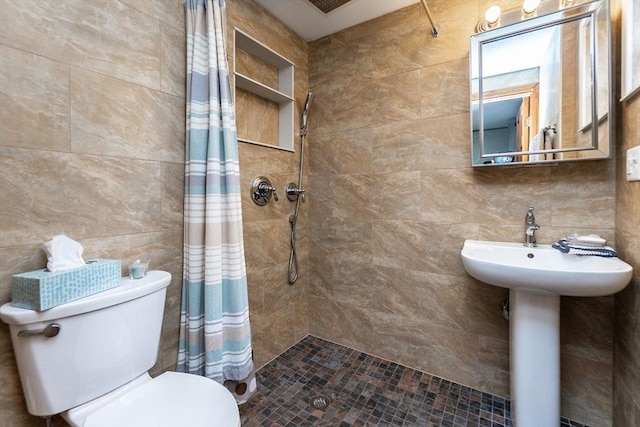 bathroom with toilet, tile walls, and tiled shower