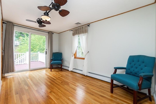 living area with plenty of natural light, visible vents, light wood-type flooring, and ceiling fan