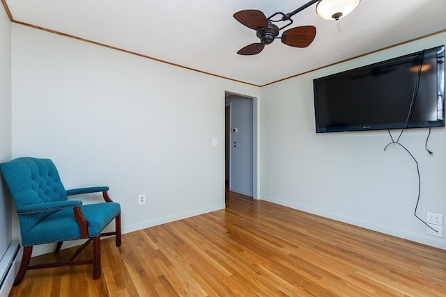 sitting room featuring baseboards, ornamental molding, ceiling fan, baseboard heating, and light wood finished floors