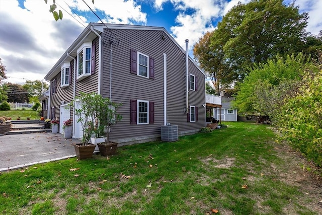 view of home's exterior featuring a lawn, central air condition unit, driveway, and an attached garage