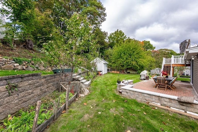 view of yard featuring an outdoor structure, a garden, stairway, and a patio
